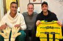 Canaries players Adam Idah, left, and Angus Gunn, right, with Chris Reeve of Talk Norwich City with items donated to a Big C charity raffle