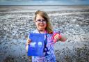 Amaya Edwards on Heacham Beach with a copy of her latest book and the spade she uses to save jellyfish