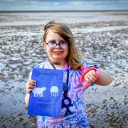 Amaya Edwards on Heacham Beach with a copy of her latest book and the spade she uses to save jellyfish