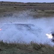 A car driving along the flooded Beach Road at Brancaster